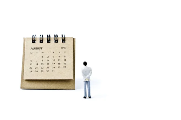 August. Calendar sheet and miniature plastic man on white backgr — Stock Photo, Image