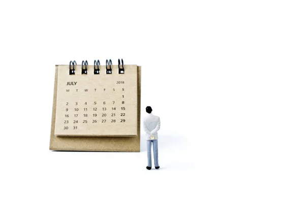 Lipca. Kalendarz, kartka i miniaturowe z tworzywa sztucznego człowieka na biały backgrou — Zdjęcie stockowe