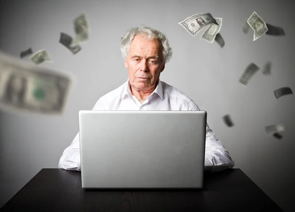 Oude man met behulp van een laptop. Oude man in het wit verdient dollar op de in — Stockfoto