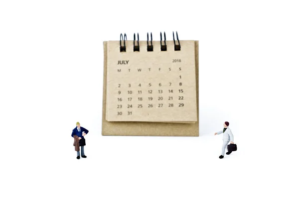 Juli. Kalender blad en miniatuur kunststof zakenlieden op wit — Stockfoto