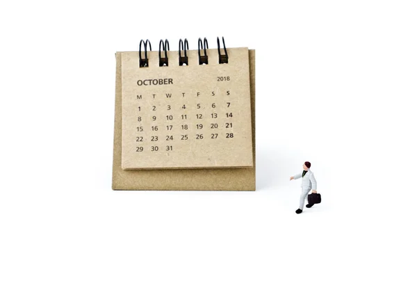 October. Calendar sheet and miniature plastic businessman on white — Stock Photo, Image