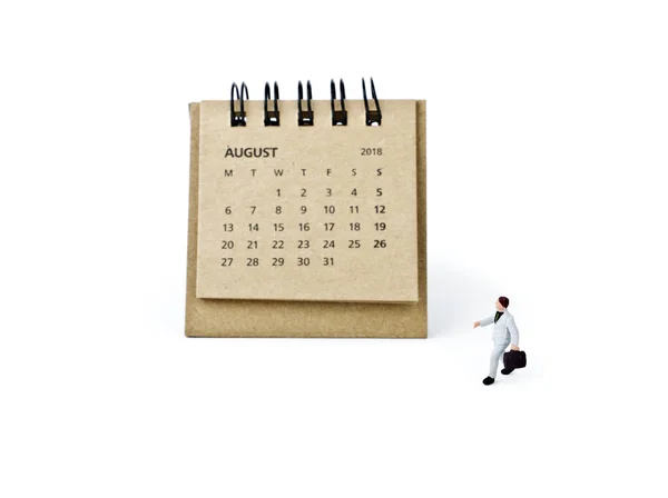 Augusti. Kalender för balansräkningen och miniatyr plast affärsman på vit — Stockfoto