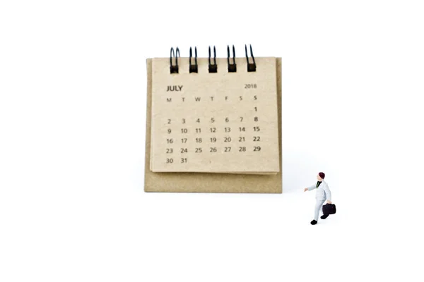 Julio. Hoja de calendario y empresario plástico en miniatura en blanco — Foto de Stock