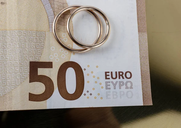 Két jegygyűrű és valuta. Esküvői vagy válási koncepció. Jogdíjmentes Stock Képek