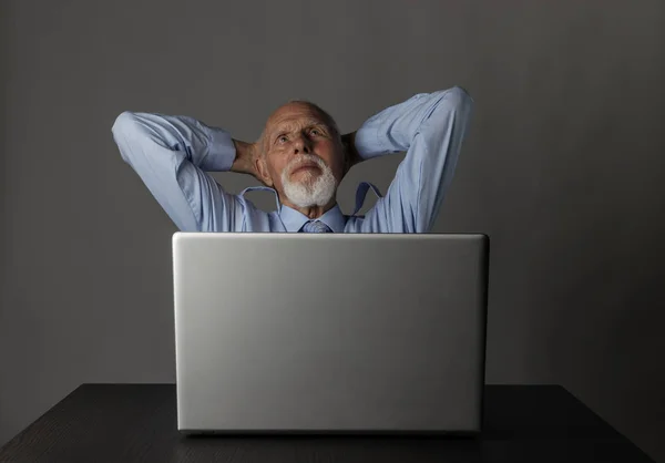 Old man using a laptop. Successful businessman is dreaming. — Stock Photo, Image