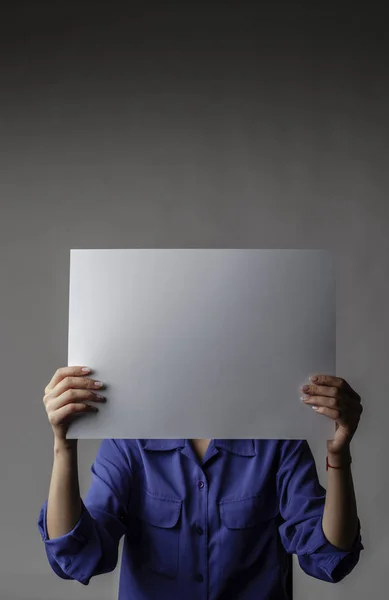 Jonge vrouw in het blauw houdt wit papier. — Stockfoto