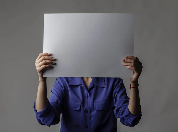 Jonge vrouw in het blauw houdt wit papier. — Stockfoto