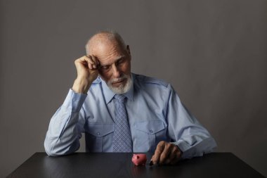 Kumbarayı tutan yaşlı adam. Ekonomi ve tasarruf.