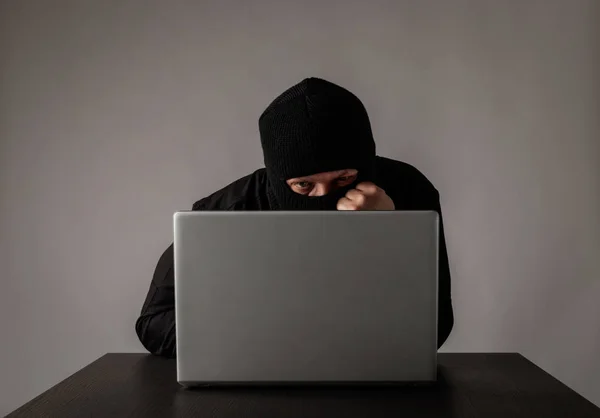 Hacker i mask med hjälp av en bärbar dator. — Stockfoto