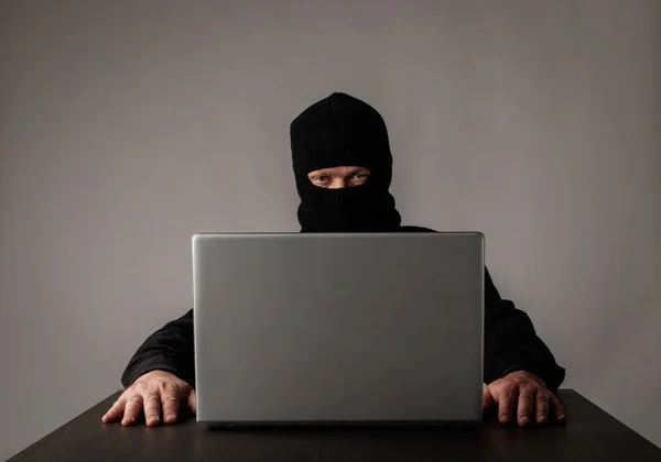 Hacker in masker met behulp van een laptop. — Stockfoto