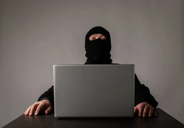 Hacker in masker met behulp van een laptop. — Stockfoto