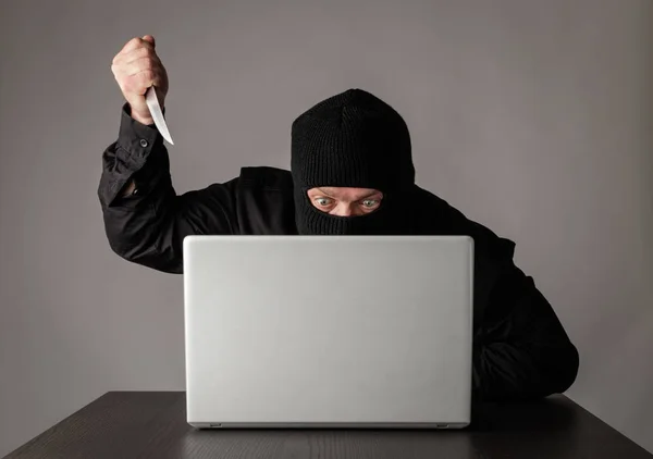 Hacker em máscara usando um laptop . — Fotografia de Stock