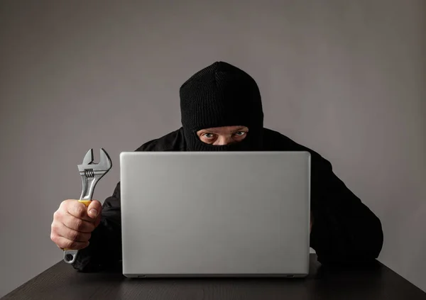 Hacker i mask med hjälp av en bärbar dator. — Stockfoto