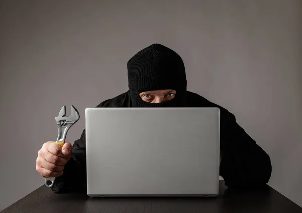 Hacker in mask using a laptop. — Stock Photo, Image