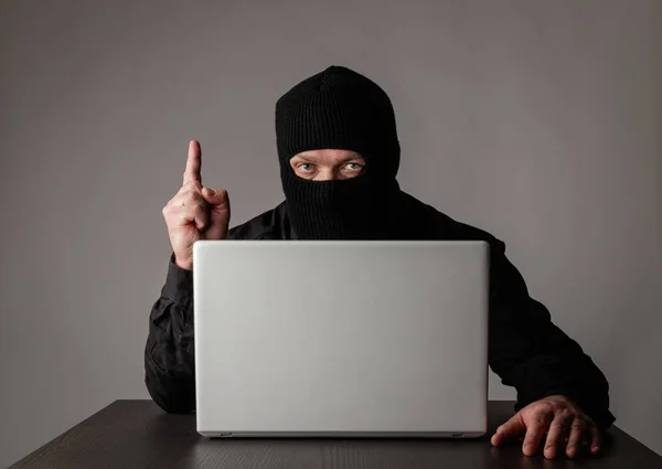 Hacker em máscara usando um laptop . — Fotografia de Stock