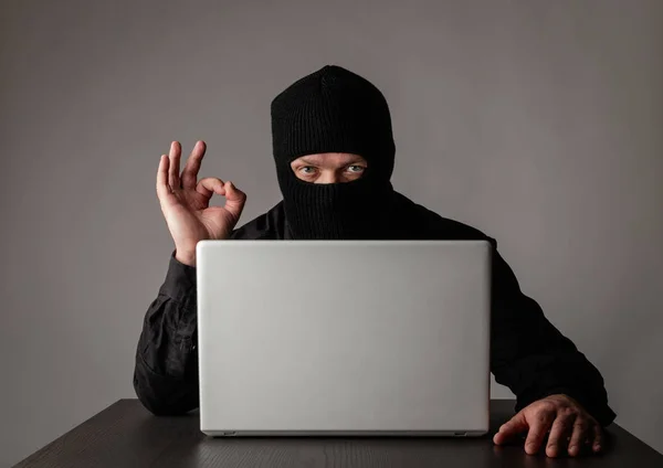 Hacker in masker met behulp van een laptop. — Stockfoto
