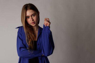 Young attractive woman in blue on gray background.