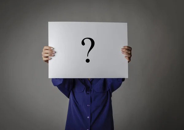 Young woman in blue is holding white paper. Question Mark. — Stockfoto