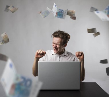 Young happy man with laptop and falling Euro banknotes. Success 