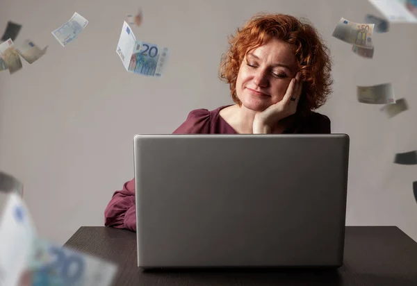 Rudowłosa kobieta z laptopem. Rudowłosa kobieta i upadające euro — Zdjęcie stockowe