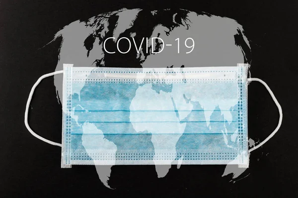 用Covid 19文字和世界地图在黑色背景上贴上医用防护面具 外科口罩 中国高头牛爆发的概念 图库图片