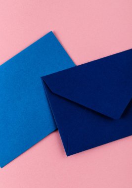 Pembe arka planda mavi zarflar. Posta zarfları masanın üstünde..