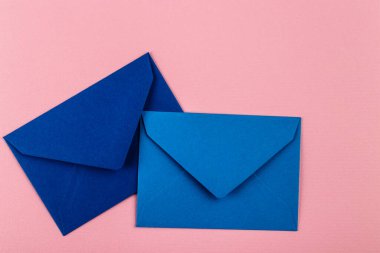 Pembe arka planda mavi zarflar. Posta zarfları masanın üstünde..