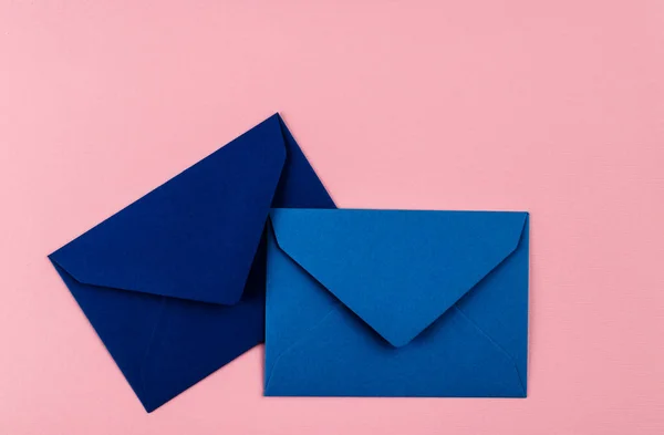 Blue envelopes on a pink background. Mail envelopes on the table.