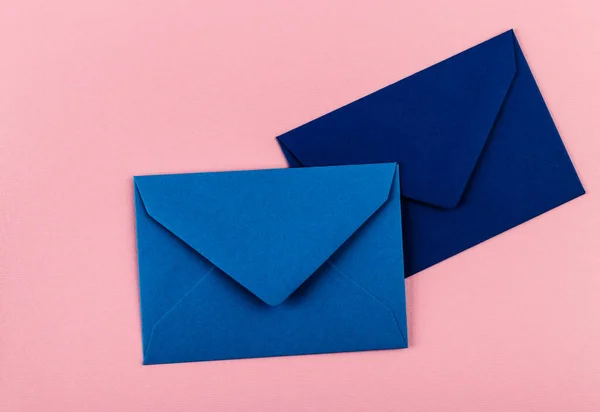 Blue envelopes on a pink background. Mail envelopes on the table.