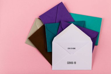 Pembe arka planda renkli zarflar. Covid-19 'dan dünyaya bir mesaj. COVID-19 krizi ve karantina konsepti. Evde kal..