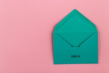 Pembe arka planda renkli bir zarf. Covid-19 'dan dünyaya bir mesaj. COVID-19 krizi ve Karantina kavramı.