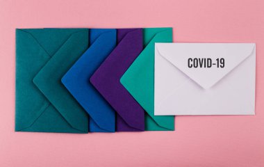 Pembe arka planda renkli zarflar. Covid-19 'dan dünyaya bir mesaj. COVID-19 krizi ve Karantina kavramı.