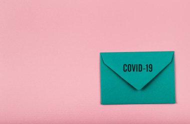Pembe arka planda renkli bir zarf. Covid-19 'dan dünyaya bir mesaj. COVID-19 krizi ve Karantina kavramı.