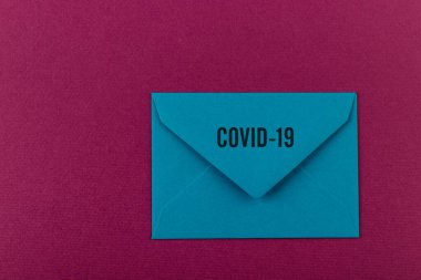 Mor arka planda renkli bir zarf. Covid-19 'dan dünyaya bir mesaj. COVID-19 krizi ve Karantina kavramı. 