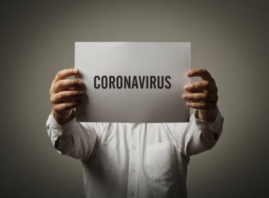 Adamın elinde Coronavirus yazan beyaz bir kağıt var. Man ve Covid-19. COVID-19 krizi ve kendini izolasyon kavramı