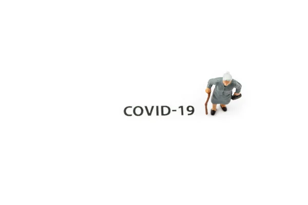 老婦人とコロナウイルスの発生 白色の背景にCovid 19に関する小さなフィギュアとテキスト コロナウイルスの予防 社会的距離と隔離の概念 — ストック写真