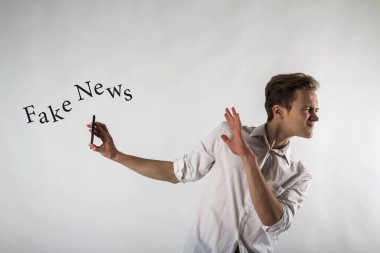 Akıllı telefonu elinde tutan genç bir adam. Antipati, nefret ve reddetme konsepti. Sahte haberleri kabul etme..