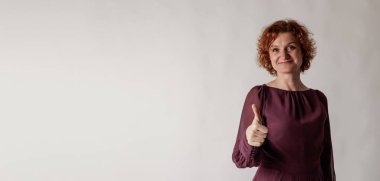 Kızıl saçlı kadın baş parmağını gösteriyor. Mutlu kadın. Başarı, mutluluk ve iyi hisler..