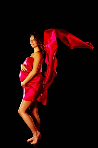Mulher grávida bonita embrulhando em material vermelho — Fotografia de Stock
