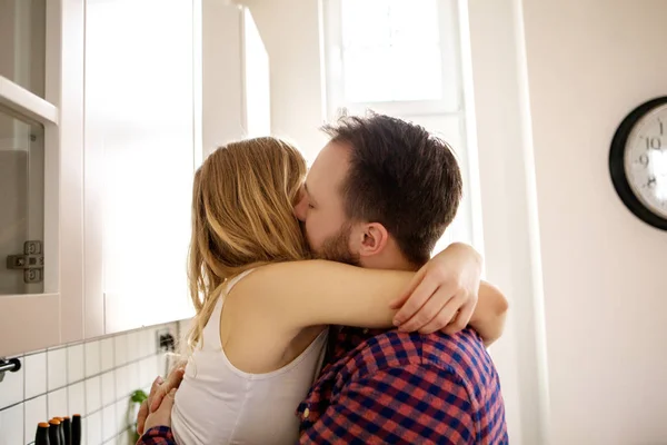 Jovem casal bonito beijando na cozinha . — Fotografia de Stock