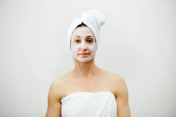 Mooie midden leeftijd vrouw met een klei masker op haar gezicht. — Stockfoto