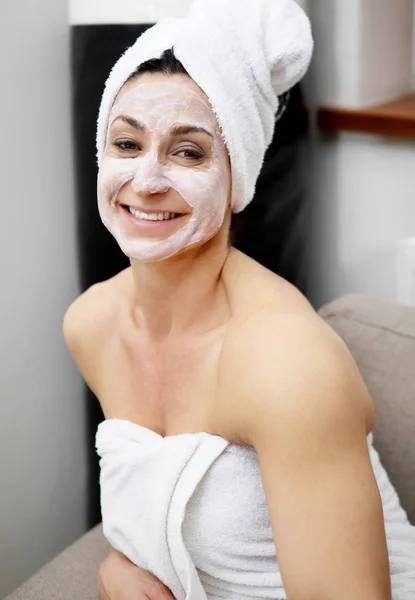 Mooie midden leeftijd vrouw met een klei masker op haar gezicht. — Stockfoto