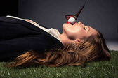 Seitenansicht der verführerischen Frau im Gras liegend mit Golfball im Mund