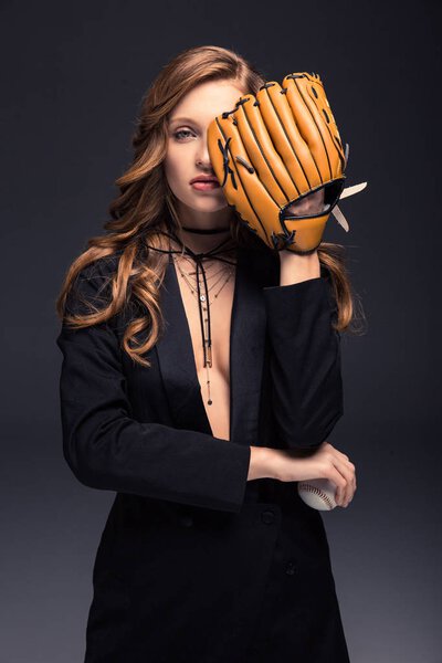 sexy woman covering eye with baseball mitt isolated on gray
