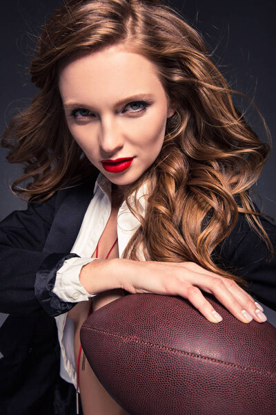 portrait of attractive woman holding american football ball isolated on gray