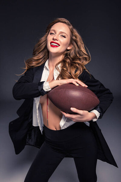 happy woman with curly hair holding american football ball