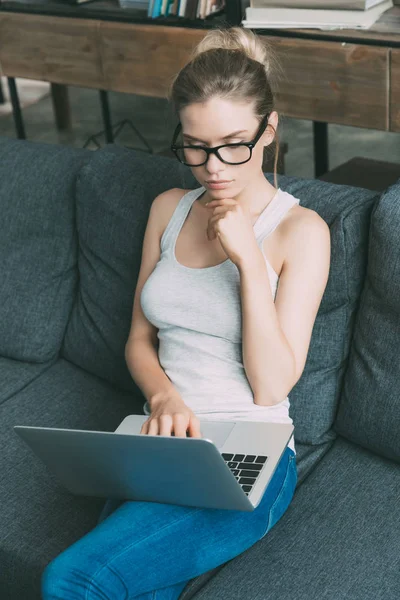 Mujer en sofá con portátil - foto de stock