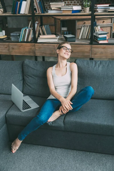 Femme sur canapé avec ordinateur portable — Photo de stock