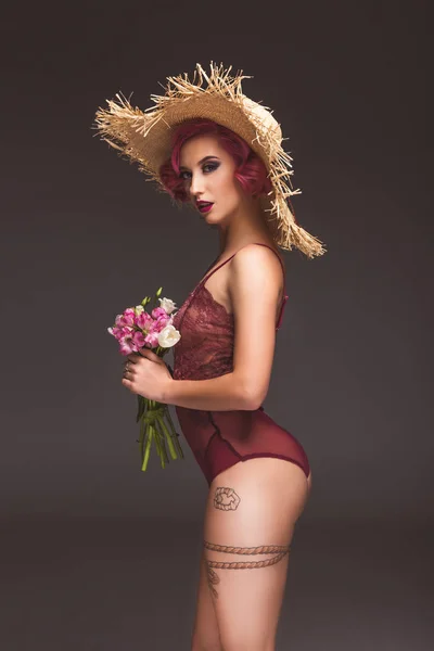 Sexy tatoué pin up fille avec des fleurs infront de fond gris — Photo de stock