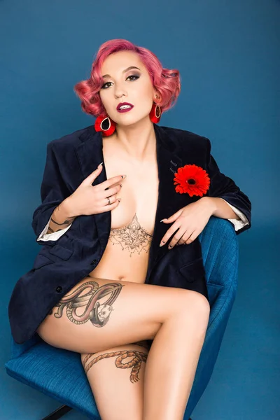 Sexy moitié nu pin up fille en veste posant sur fauteuil infront de fond bleu — Photo de stock